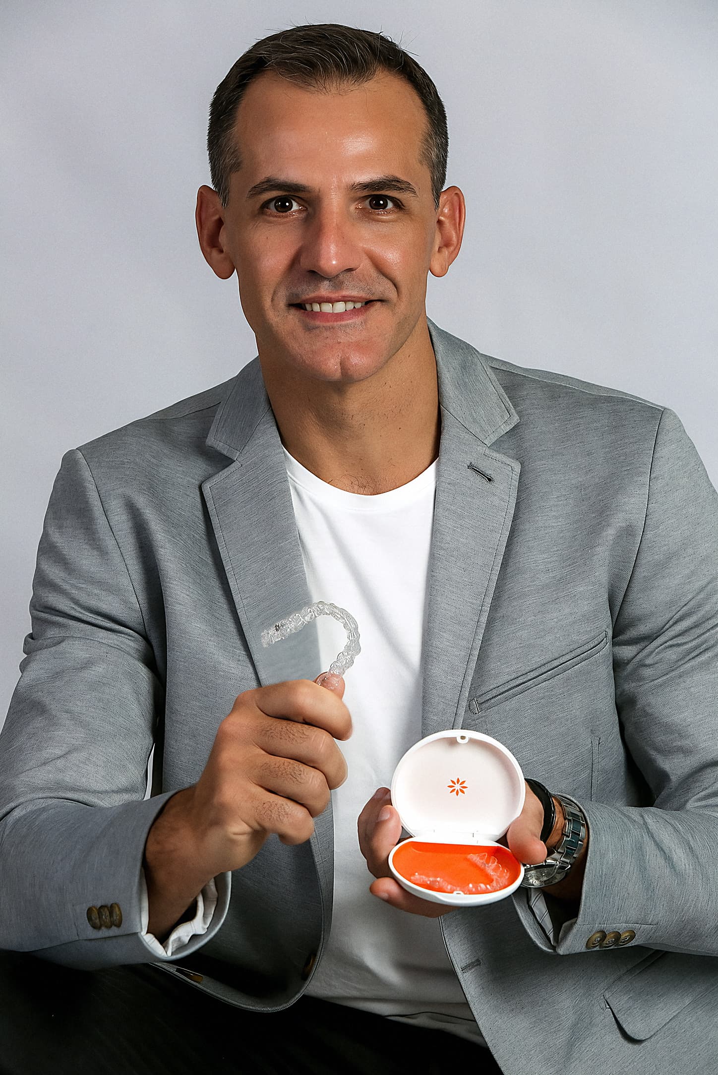 Dr. Marcelo Nunes segurando um alinhador Invisalign e seu estojo